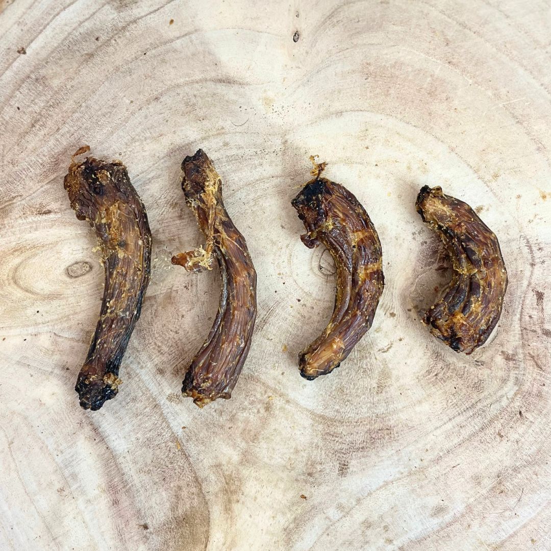 Four all natural dried chicken necks on a wooden background