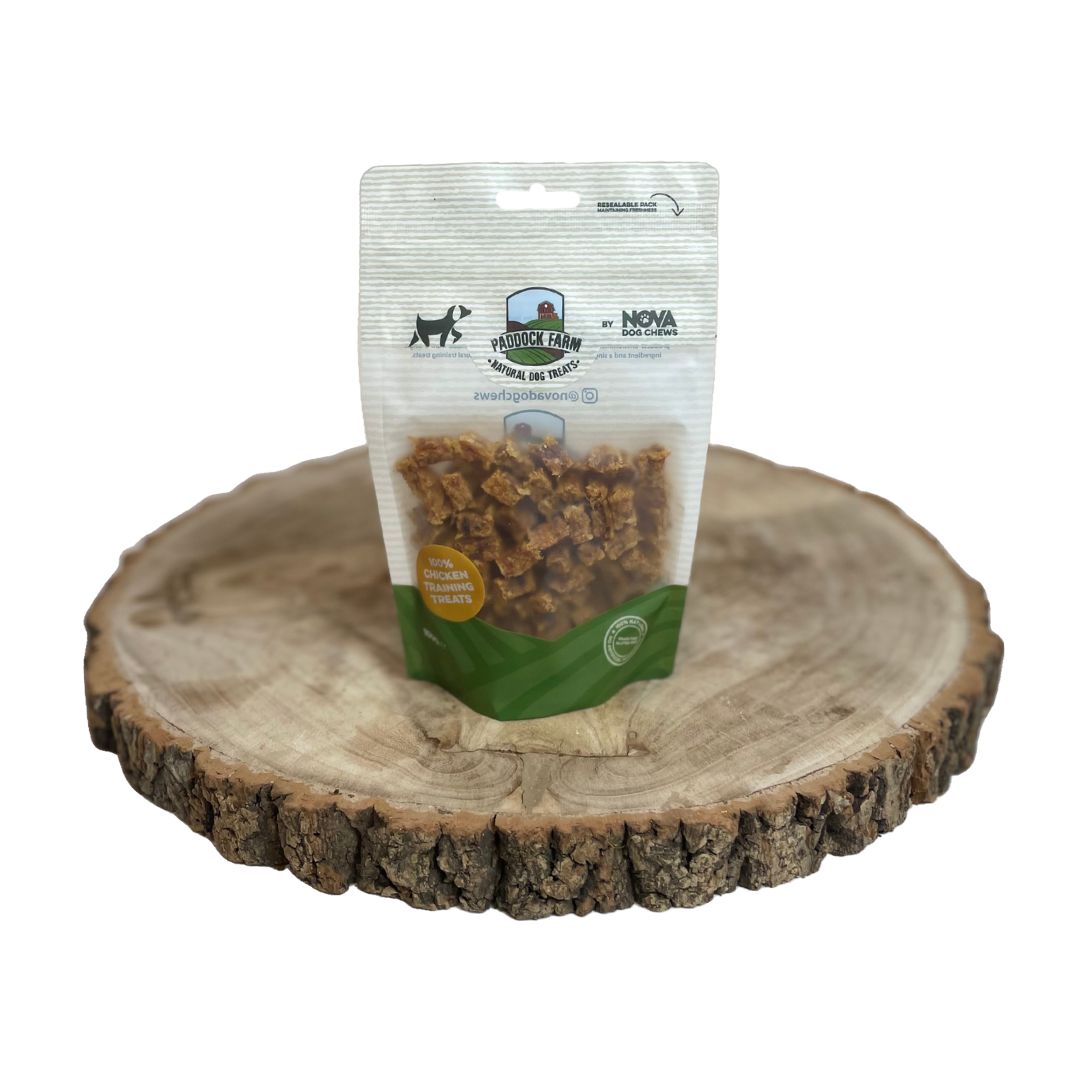 A bag of all natural dog dried training treats made of chicken on a wooden block on a plain white background