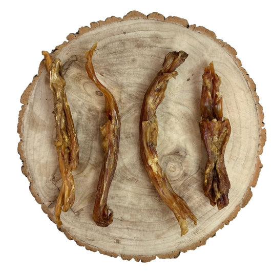 Four all natural dried beef achilles tendon on a wooden background