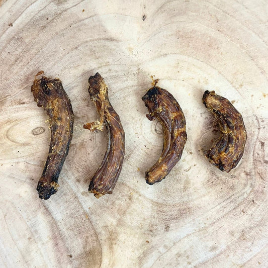 Four all natural dried chicken necks on a wooden background