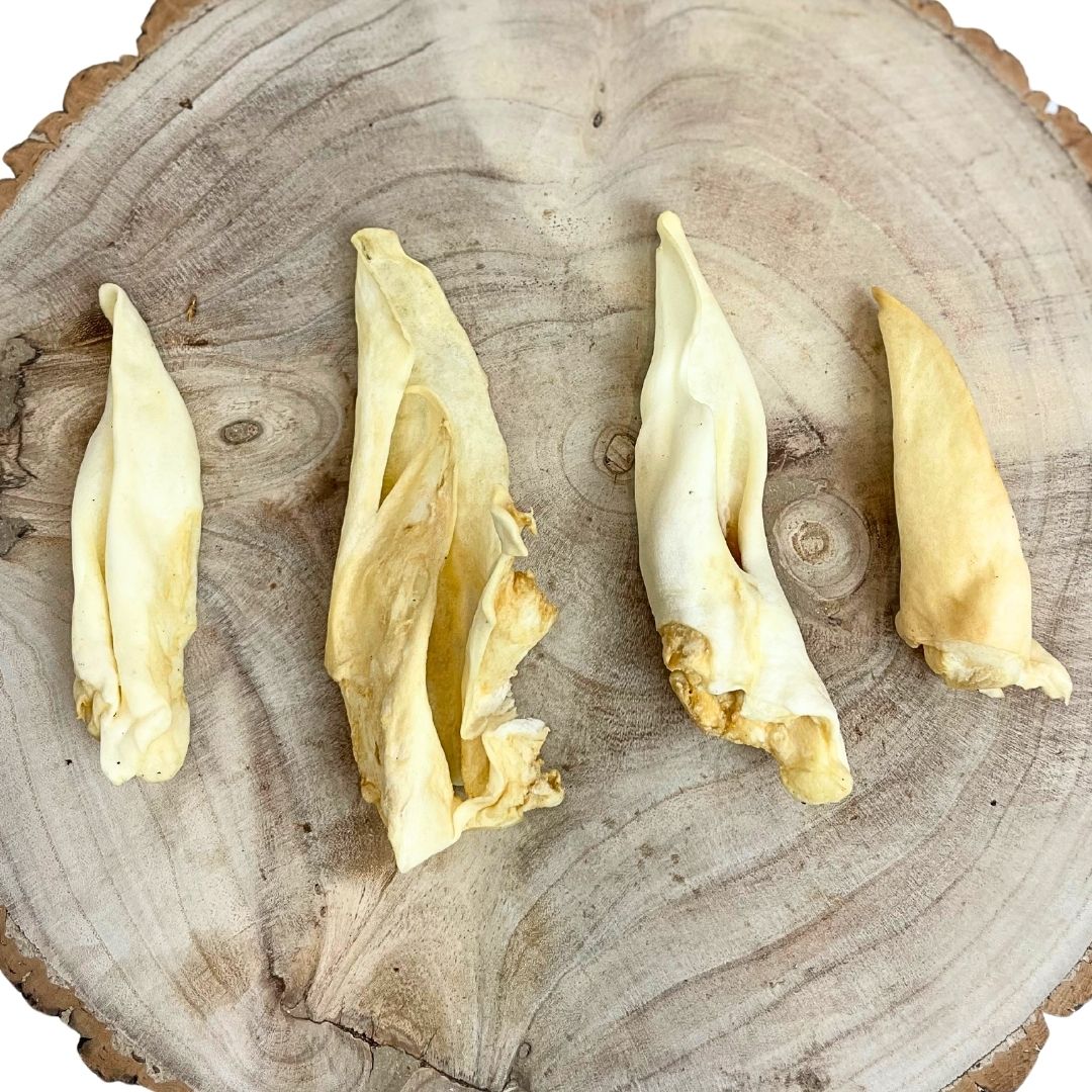 Four all natural dried lamb ears on a wooden background