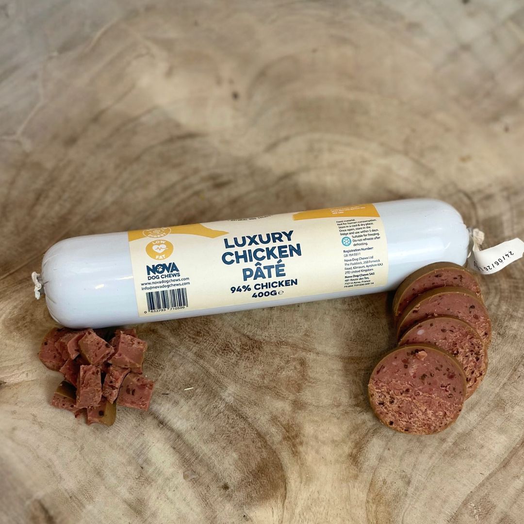 All natural luxury chicken pate in a tube with slices and diced cubes in fron on a wooden background