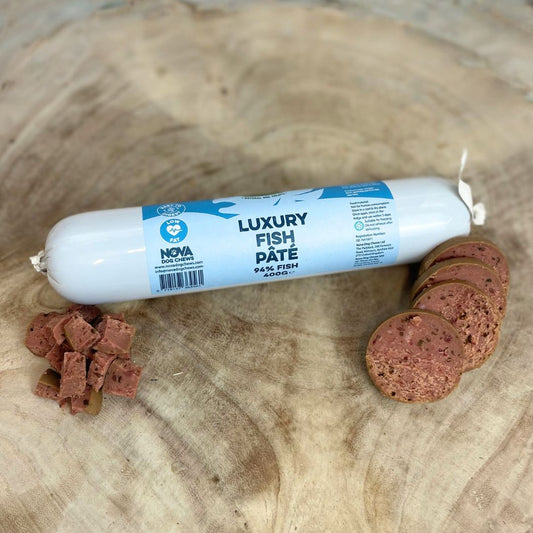 All natural luxury fish pate in a tube with slices and diced cubes in front on a wooden background