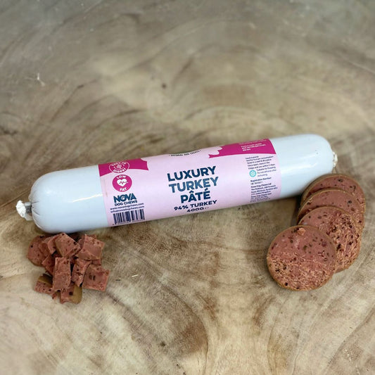 All natural luxury Turkey pate in a tube with slices and diced cubes in front on a wooden background