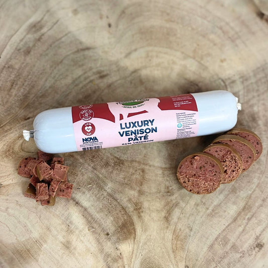 All natural luxury venison pate in a tube with sliced sections and diced cubes in front on a wooden background
