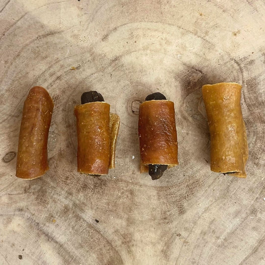 Four all natural dried pigs in blankets on a wooden background 